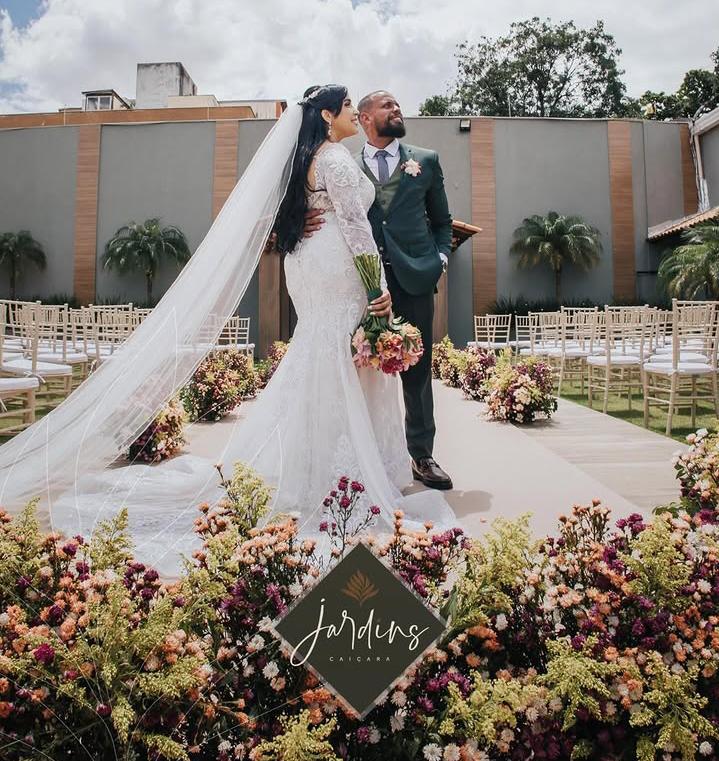 Casal recém-casado no altar do Jardins Caiçara, cercado por flores