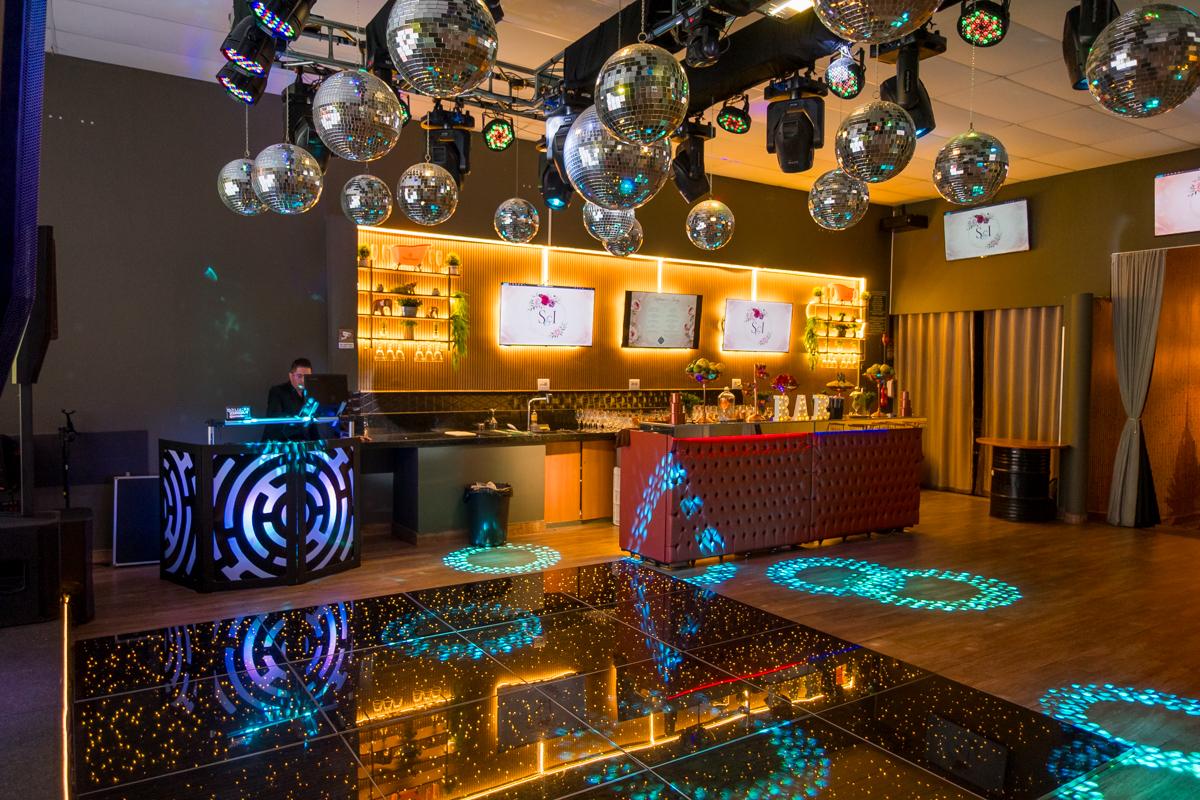 Pista de dança iluminada com globos espelhados e bar