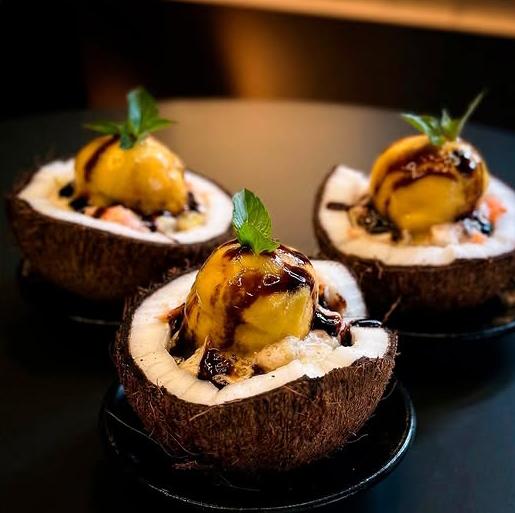 Sobremesa em casca de coco com sorvete e calda